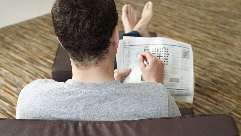Ein junger Mann löst ein Sudoku und ein Kreuzworträtsel, um sein Gedächtnis zu trainieren.