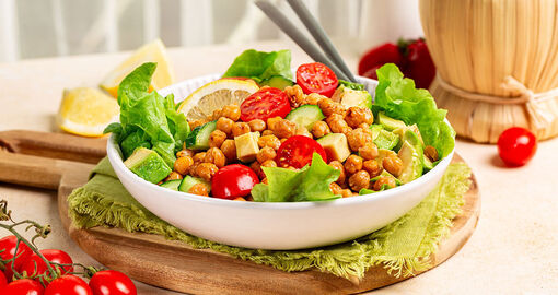Ein Teller gefüllt mit Salat - Gurke, Avocado, Tomate, Kiechererbsen.