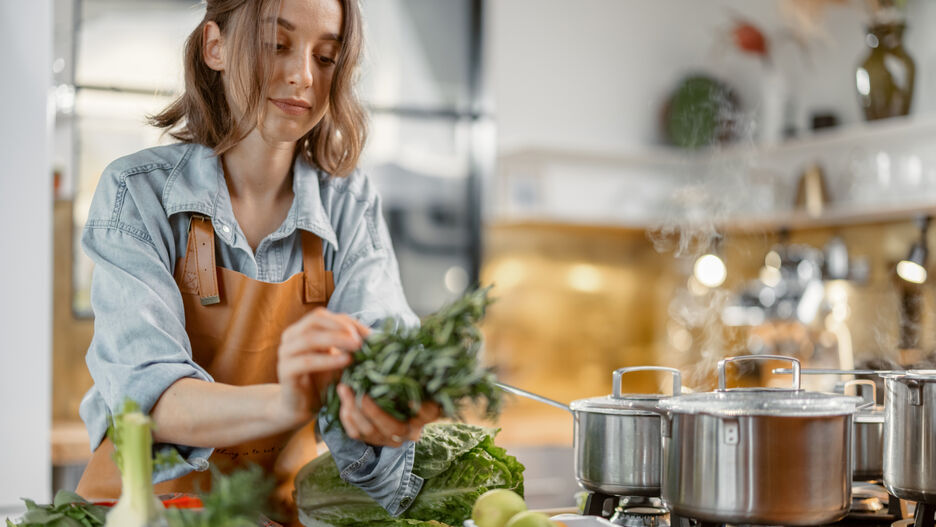Eine junge Frau wäscht Gemüse und bereitet ein gesundes, nährstoffreiches Essen zu.