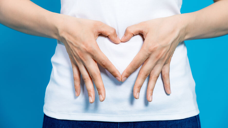 Eine Person formt vor Ihrem Bauch mit den Händen ein Herz.