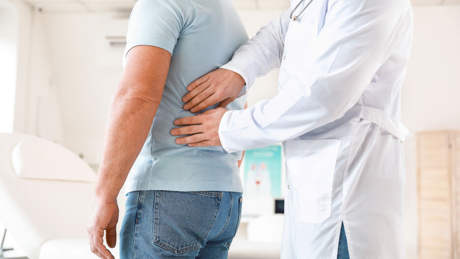 Ein Arzt tastet einen Patienten ab.
