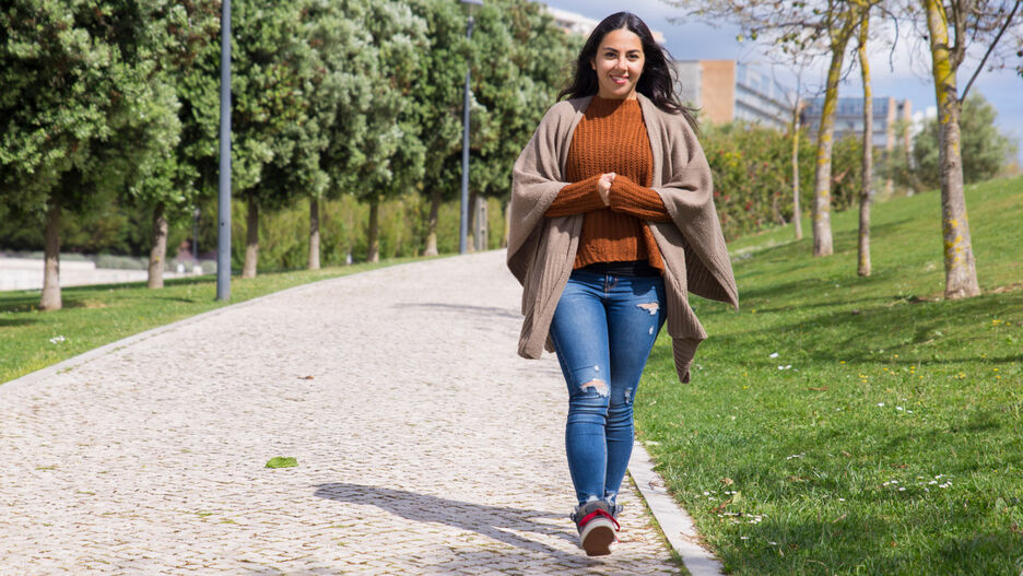 Eine junge Frau geht bei strahlendem Sonnenschein spazieren.