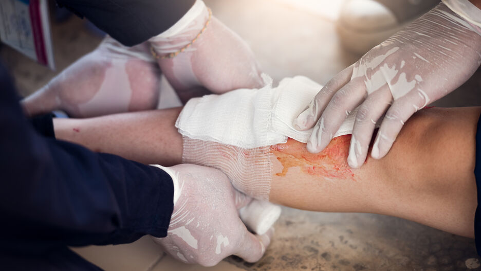 Zwei Sanitäter legen einer verletzten Person einen Verband um, um die Blutung zu stoppen.