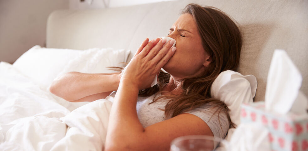 Frau liegt im Bett_Erkältung oder Grippe - Die Symptome von Grippe, Erkältung, Allergie und Coronavirus können sich auf den ersten Blick ähneln.