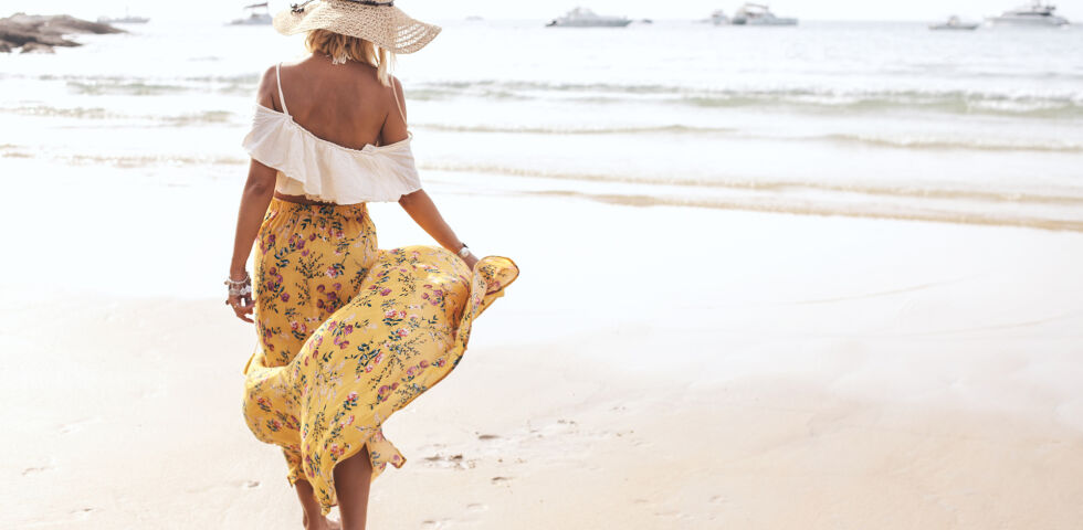 Frau geht am Strand spazieren_Sommer_Meer_shutterstock_1635973441 - Mallorca-Akne ist eine Sonderform der Sonnenallergie.